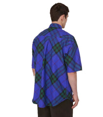 Person wearing a blue and green plaid shirt on a white background