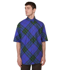 Man wearing a blue and green plaid shirt on a light gray background