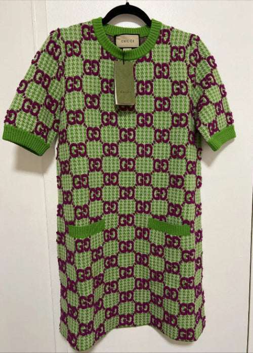 Green and purple patterned baby outfit on a hanger against a white background