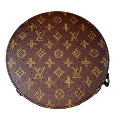 Round brown leather bag with gold monogram pattern on a marble surface