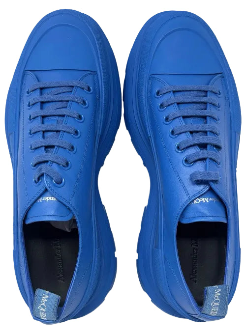 A pair of Alexander McQueen low-top sneakers in a vibrant royal blue color, featuring matching blue laces and chunky soles, shown from a top-down view on a white background.