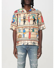Person wearing a colorful patterned shirt and jeans on a white background