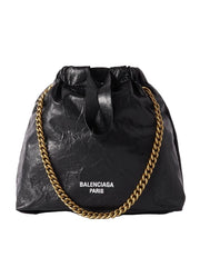 Black bag with gold chain and Balenciaga branding on a white background