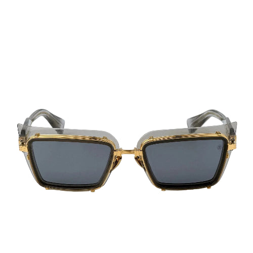 Sunglasses with gold frame and dark lenses on a light gray background