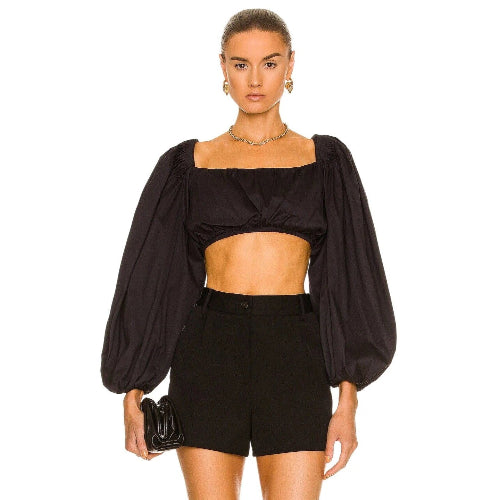 Woman wearing a black outfit with puffed sleeves on a white background