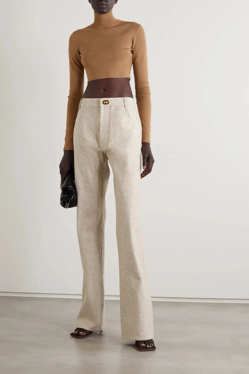 Person wearing a brown top, beige pants, and black gloves against a white background