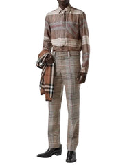 A mannequin wearing a brown and beige striped shirt, matching trousers, and a brown plaid scarf, set against a plain white background.