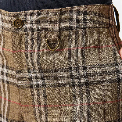 Close-up of a plaid waistband and front pocket area of tailored trousers. The fabric is a textured taupe-brown with black, beige, and thin red overcheck lines, featuring a button closure and a small brass loop detail.