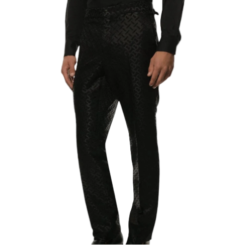 Black patterned trousers with a subtle geometric jacquard weave, shown on a model from the waist down against a light gray background.