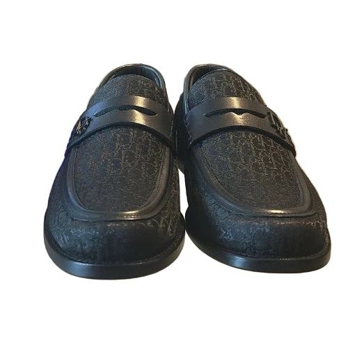 Pair of black loafers on a glass surface with a blurred background