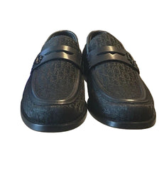 Pair of black loafers on a glass surface with a blurred background