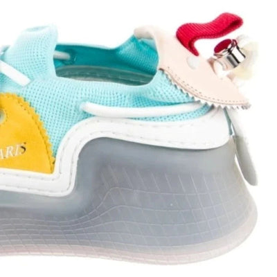 A close-up of a colorful sneaker featuring a light blue mesh upper, a translucent gray sole, a yellow side panel, and a decorative red and beige heel detail.