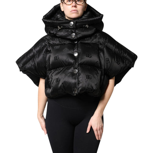 Person wearing a black puffer cape with button details on a white background