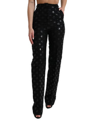 Black patterned pants worn by a person on a white background