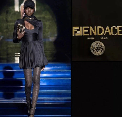 Model on a runway wearing a black outfit with a high collar, holding a product, with 'FENDACE' branding.