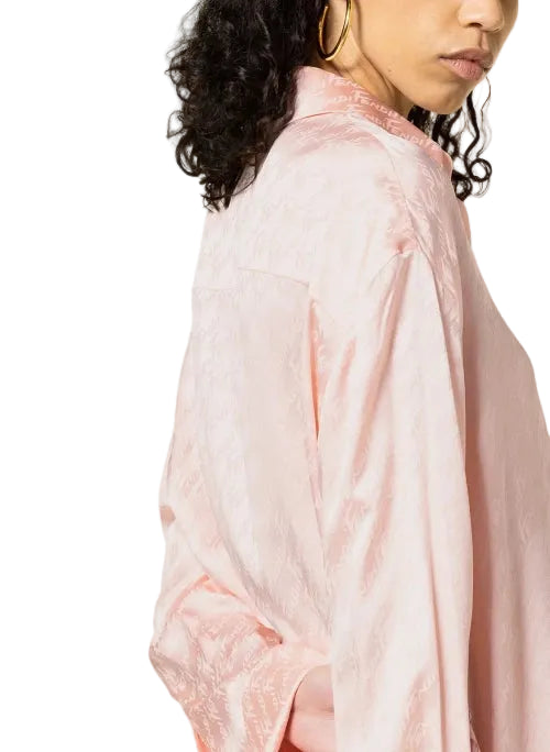 Person wearing a light pink blouse with a plain background