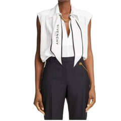 Person wearing a white blouse with a black bow and dark pants on a white background