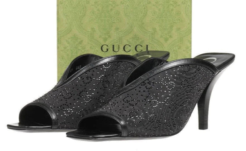 Black high-heeled shoes with glittery texture in front of a Gucci box.