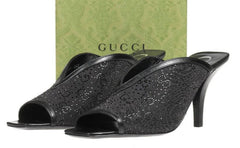 Black high-heeled shoes with glittery texture in front of a Gucci box.