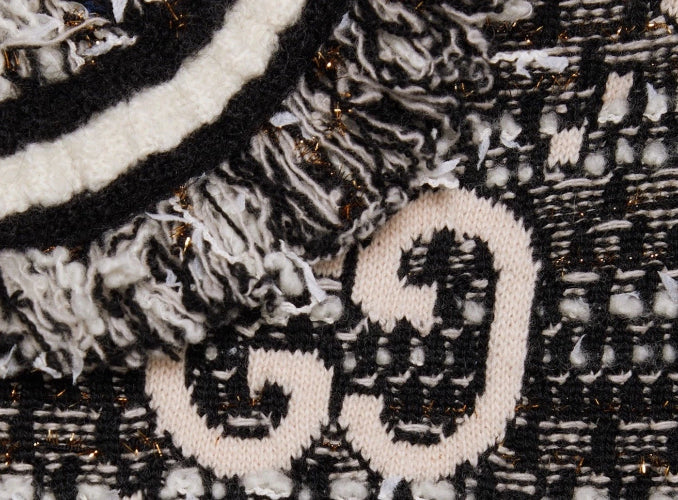 Close-up of a textured fabric with a patterned design, featuring black, white, and gold colors.