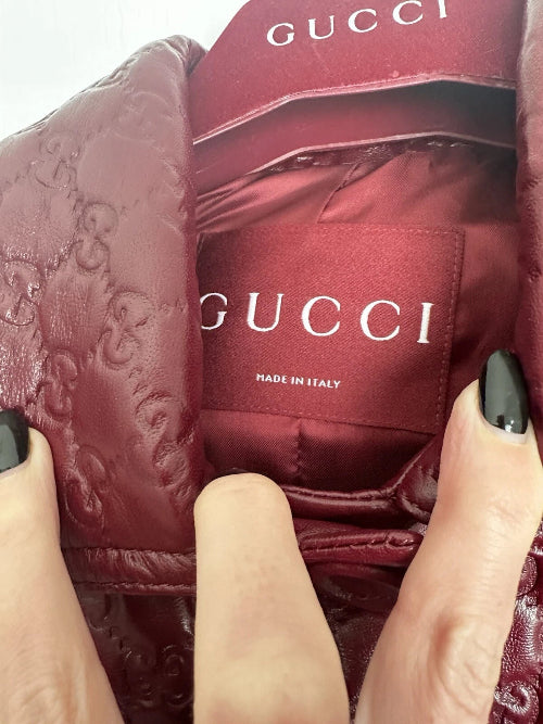 Close-up of a Gucci bag with a hand holding it, showing the brand logo.