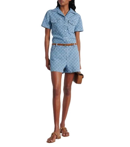 Woman wearing a blue denim romper with a white background