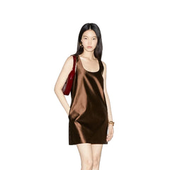Woman wearing a sleeveless dress with a plain background