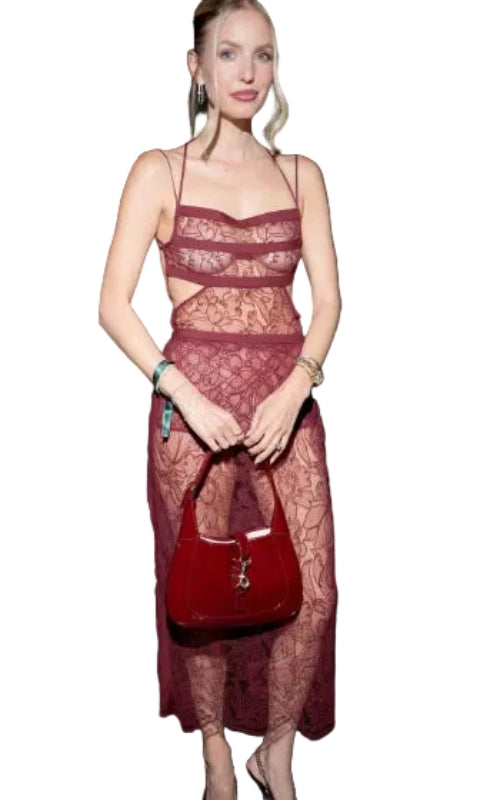 Woman in a red dress holding a matching handbag at an event.