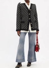 A model wearing a black and white patterned button-up shirt, light-wash wide-leg jeans, and a red handbag, shown in a cropped studio fashion shot.