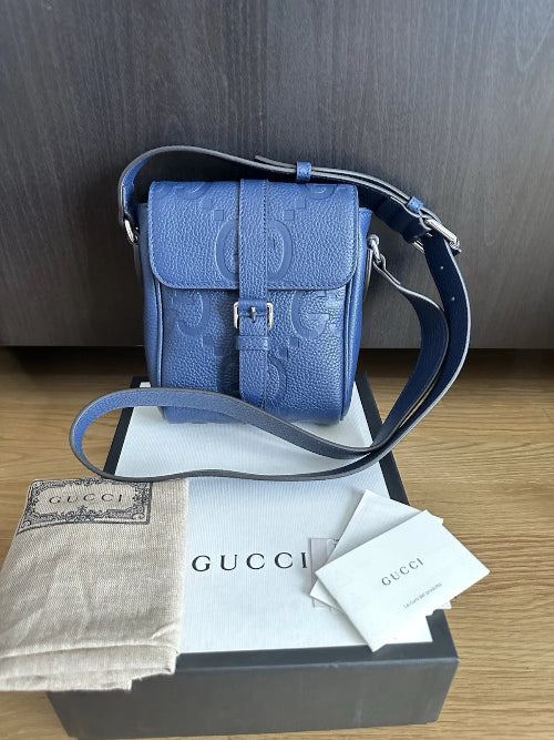 Blue Gucci handbag with matching strap on a wooden surface
