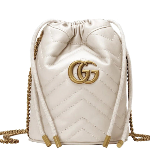 White quilted drawstring bag with gold accents and logo on a light gray background