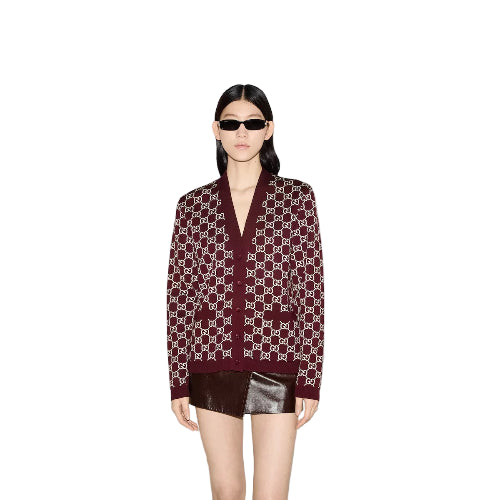 Person wearing a patterned sweater and sunglasses on a plain background