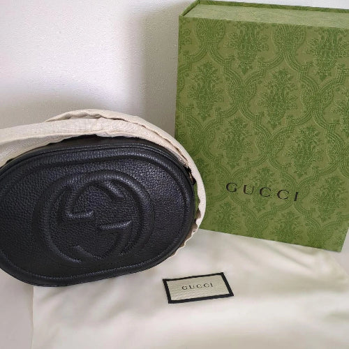 Black Gucci bag with a green patterned box on a white surface