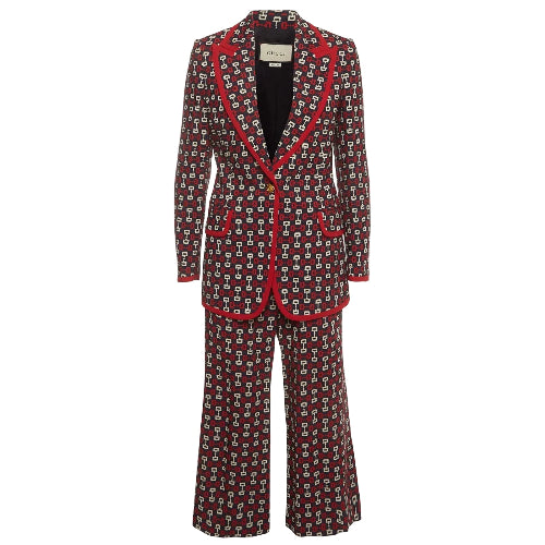 A Gucci two-piece suit featuring a dark red wide-leg blazer and matching trousers with an all-over small geometric print, accented by bright red piping along the lapels, pockets, and cuffs.
