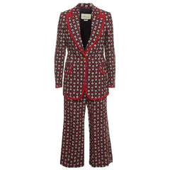 A Gucci two-piece suit featuring a dark red wide-leg blazer and matching trousers with an all-over small geometric print, accented by bright red piping along the lapels, pockets, and cuffs.