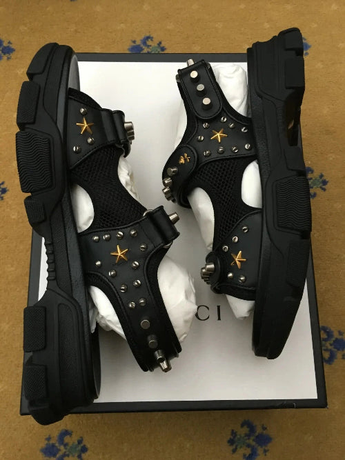 Black high-top sneakers with white soles on a black background