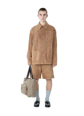 Person wearing a beige outfit with a matching bag on a white background