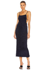 Woman wearing a navy blue dress with thin straps on a white background