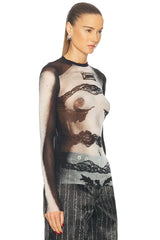 Model wearing a sheer top with lace details on a white background