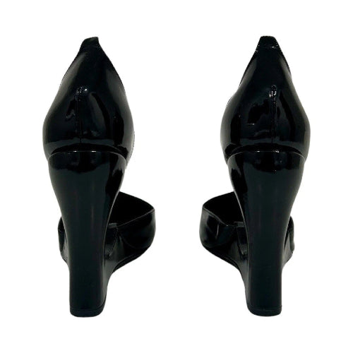 A pair of black patent leather high-heeled pumps shown from the back, featuring a pointed toe and a chunky block heel, set against a plain white background.