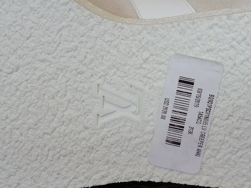 Close-up of a white textured fabric surface with an embossed LV logo and a white product tag with barcode and text.