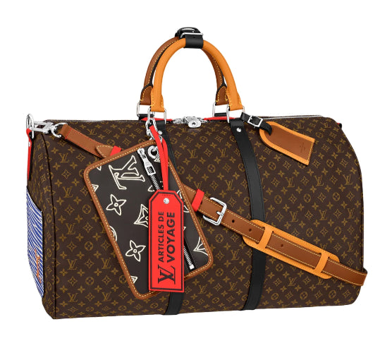 Louis Vuitton monogram duffle bag in brown coated canvas with tan leather handles and trim, black shoulder strap, silver hardware, and a red luggage tag reading 'ARTICLES DE VOYAGE'.