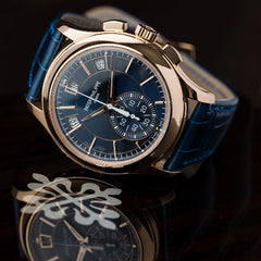 Luxury watch with blue face and leather strap on a dark background