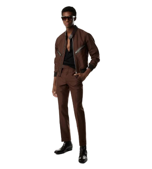 A man modeling a brown two-piece suit with a white shirt and black tie against a plain white studio background.