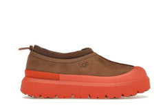 Brown slip-on shoe with a red sole on a white background