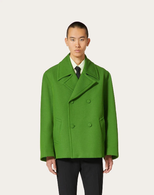 Man wearing a bright green coat on a white background