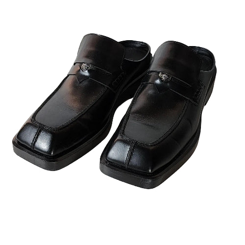 Pair of black leather shoes on a light wooden floor.