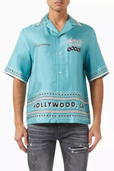 Person wearing a turquoise shirt with 'Hollywood, CA' text and 'Amiri' branding.