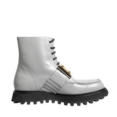 A white lace-up ankle boot with a chunky black lug sole and a gold-tone decorative buckle detail on the side, shown against a plain white background.