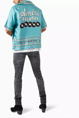 Person wearing a turquoise jacket with branding on a white background